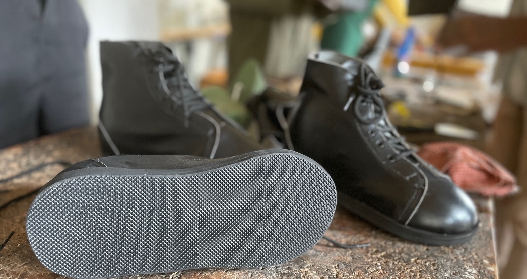 3 fertiggestellte geschlossene schwarze Schuhe stehen auf einer Werkbank