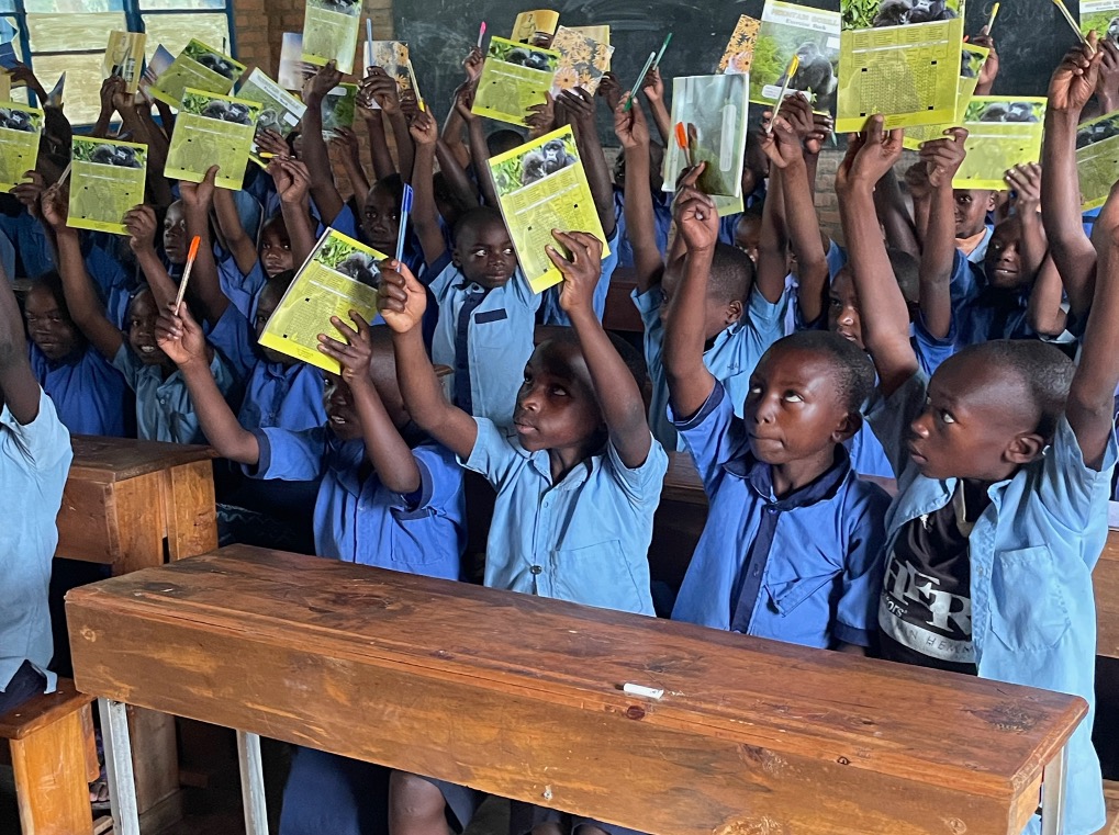 Several pupils hold up educational materials such as writing materials and information material with their hands
